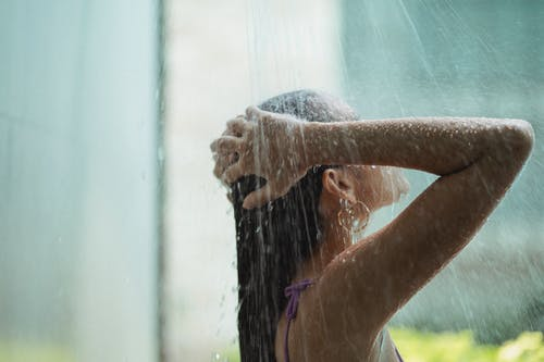 a woman washing her hair under a shower