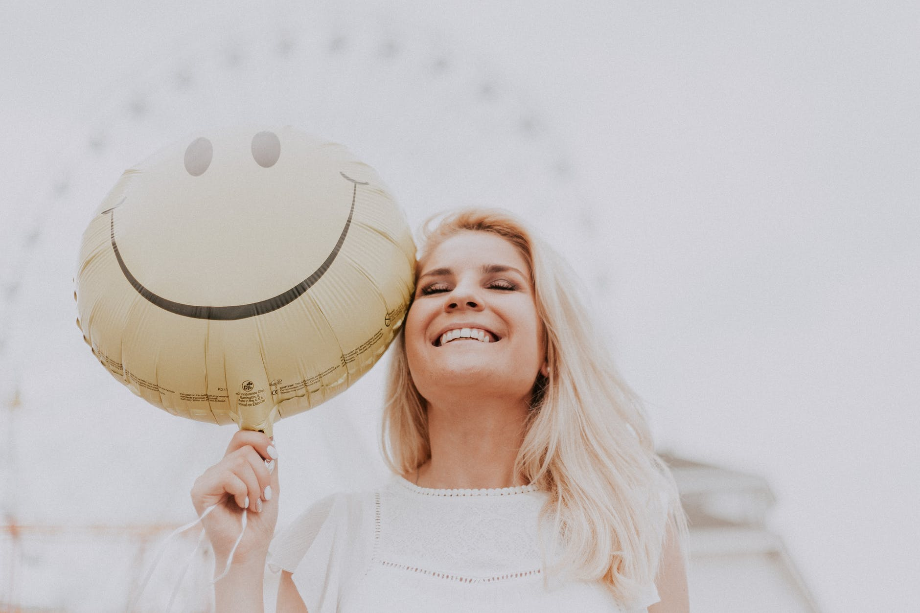 Woman holding smiley face balloon. 