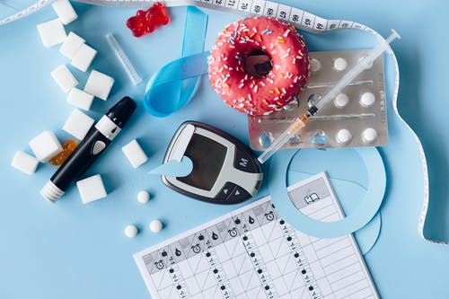 insulin injection, meds, diabetes testing machine, and donut on a table