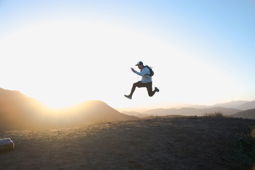 Energetic man jumping at sunrise