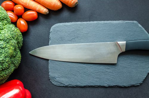  A kitchen knife next to some vegetables