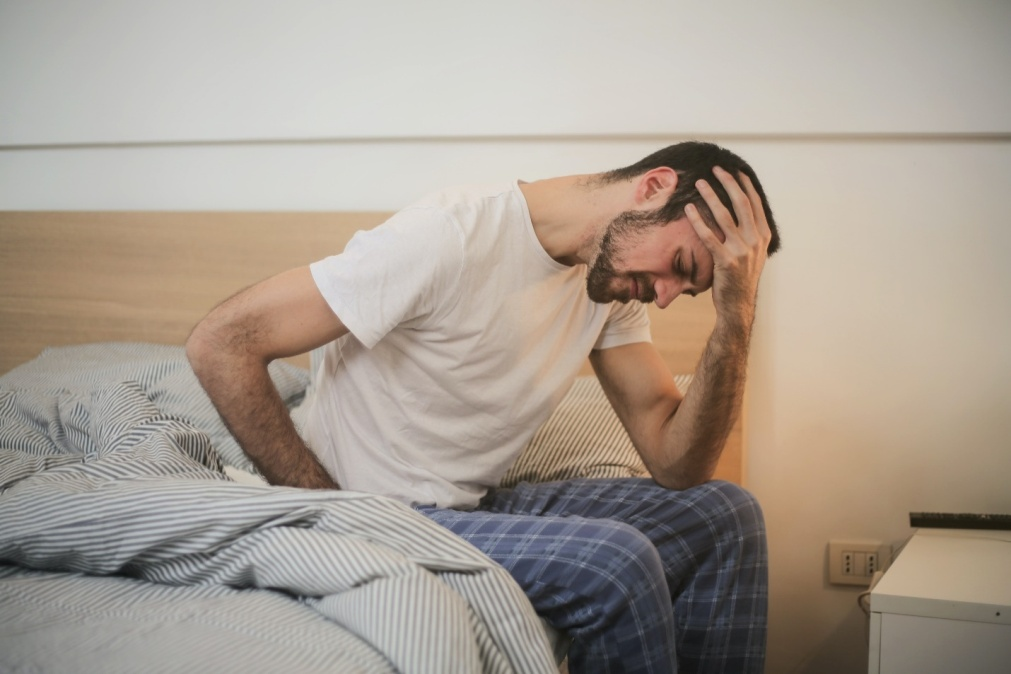 Man sitting up in his bed due to pain