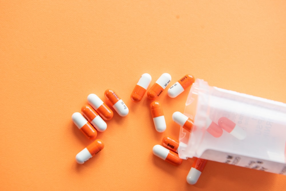 orange and white capsules spilling from a container