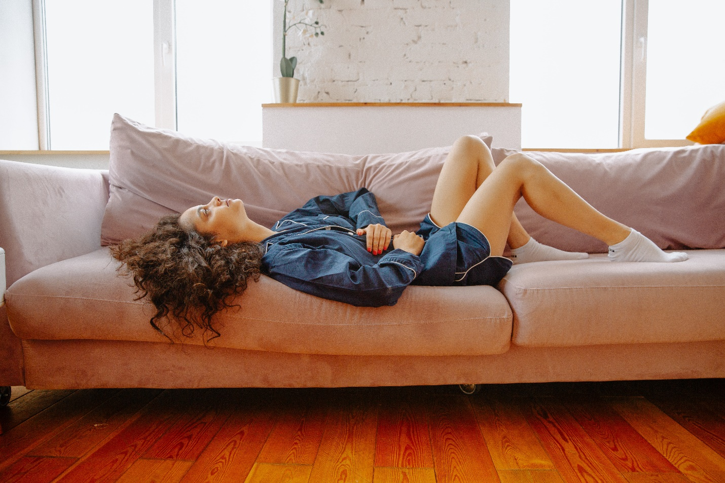 Woman laying on the couch clutching her stomach