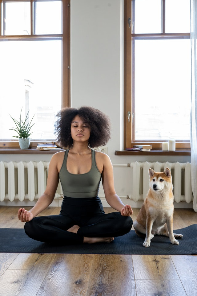 A woman meditating beside her dog