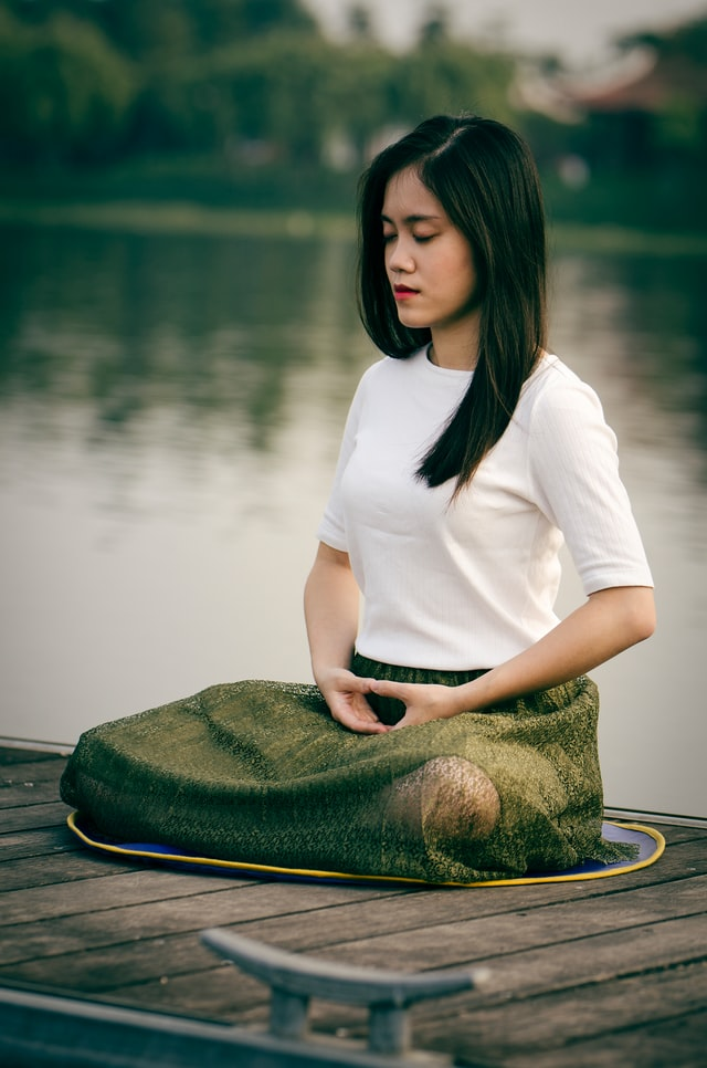 A woman meditating beside a lake