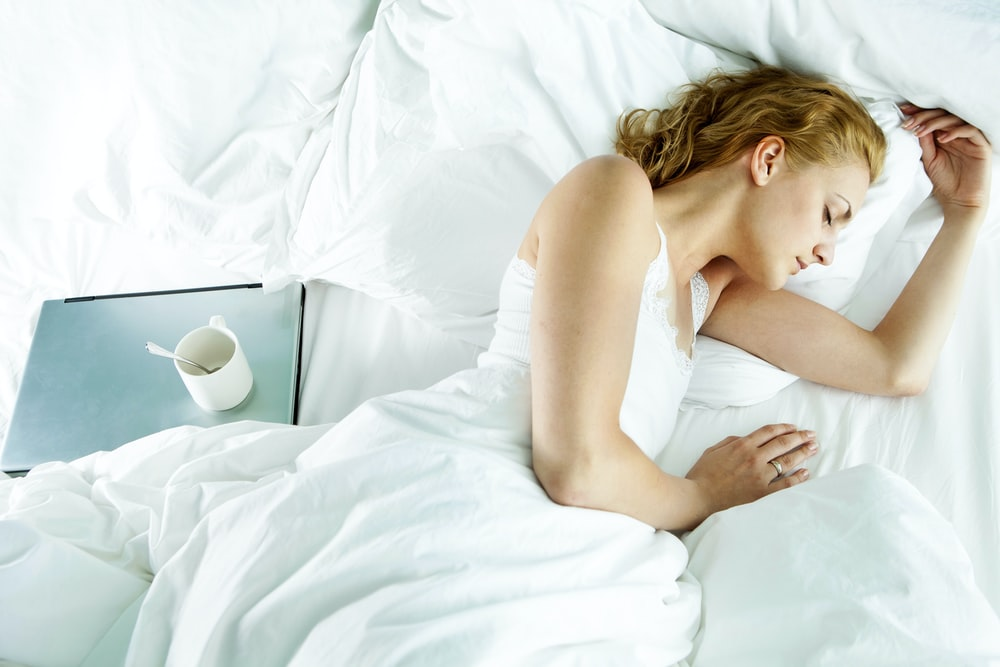 A woman napping in the day with a mug by her side